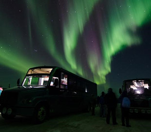 photo northern lights above people and two vehicles